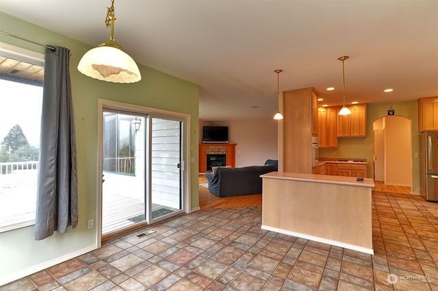 kitchen featuring hanging light fixtures, a healthy amount of sunlight, and a brick fireplace