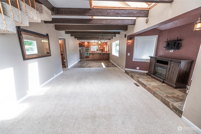 unfurnished living room with dark carpet, a barn door, beam ceiling, and a tile fireplace