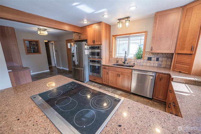 kitchen featuring appliances with stainless steel finishes, backsplash, sink, and light stone countertops