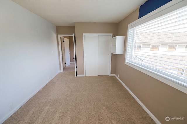 unfurnished bedroom featuring a closet and light colored carpet