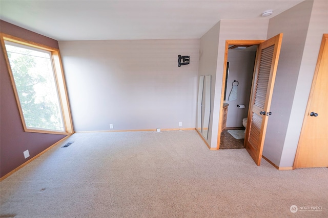 unfurnished bedroom with light colored carpet and ensuite bathroom