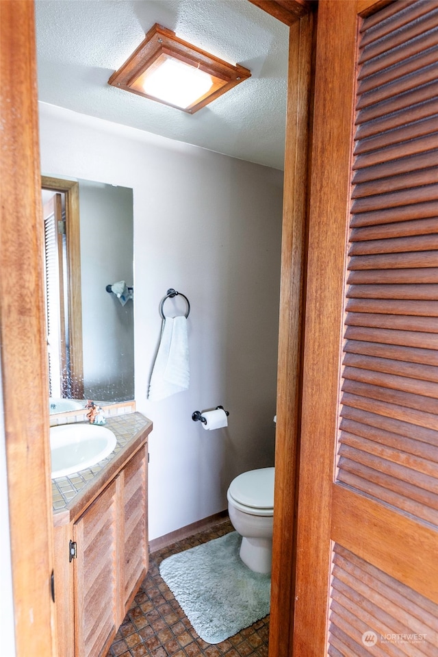 bathroom with vanity, toilet, and a textured ceiling