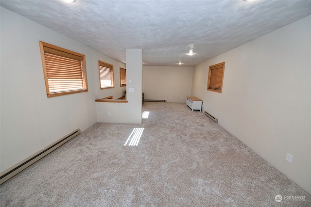 spare room with a textured ceiling, a baseboard heating unit, and light colored carpet