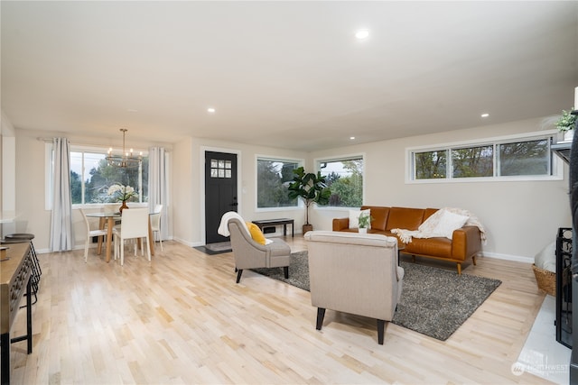 living room featuring a notable chandelier, light hardwood / wood-style flooring, and a healthy amount of sunlight