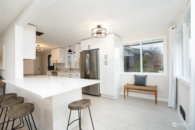 kitchen with white cabinets, a breakfast bar, kitchen peninsula, stainless steel appliances, and sink