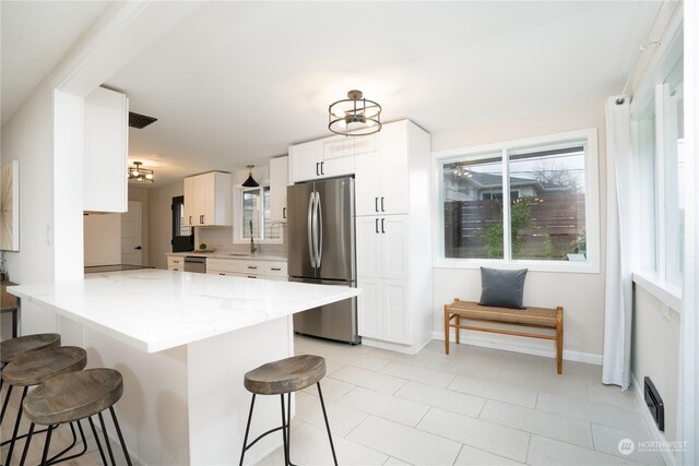 4109 N Huson St, Tacoma, WA 98407 - kitchen featuring a breakfast bar, light stone counters, a sink, stainless steel appliances, and white cabinets