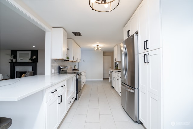 kitchen with decorative backsplash, white cabinets, kitchen peninsula, light stone countertops, and stainless steel appliances