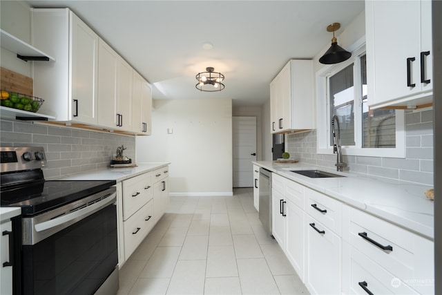 kitchen with appliances with stainless steel finishes, white cabinetry, backsplash, light tile patterned floors, and sink