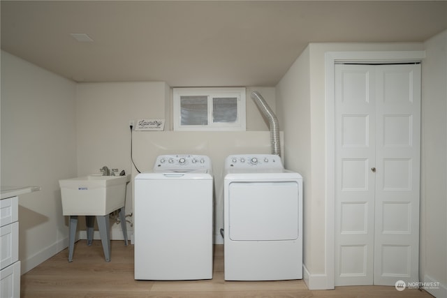 laundry room with light hardwood / wood-style floors, separate washer and dryer, and cabinets