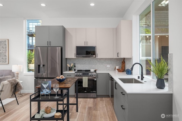 kitchen with sink, light hardwood / wood-style floors, plenty of natural light, and appliances with stainless steel finishes