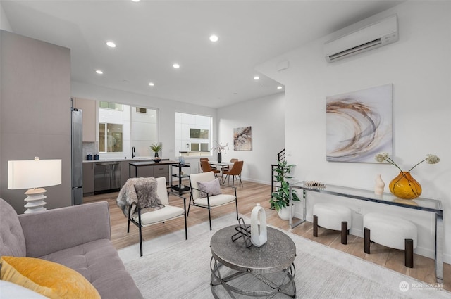 living room with an AC wall unit, light hardwood / wood-style flooring, and sink