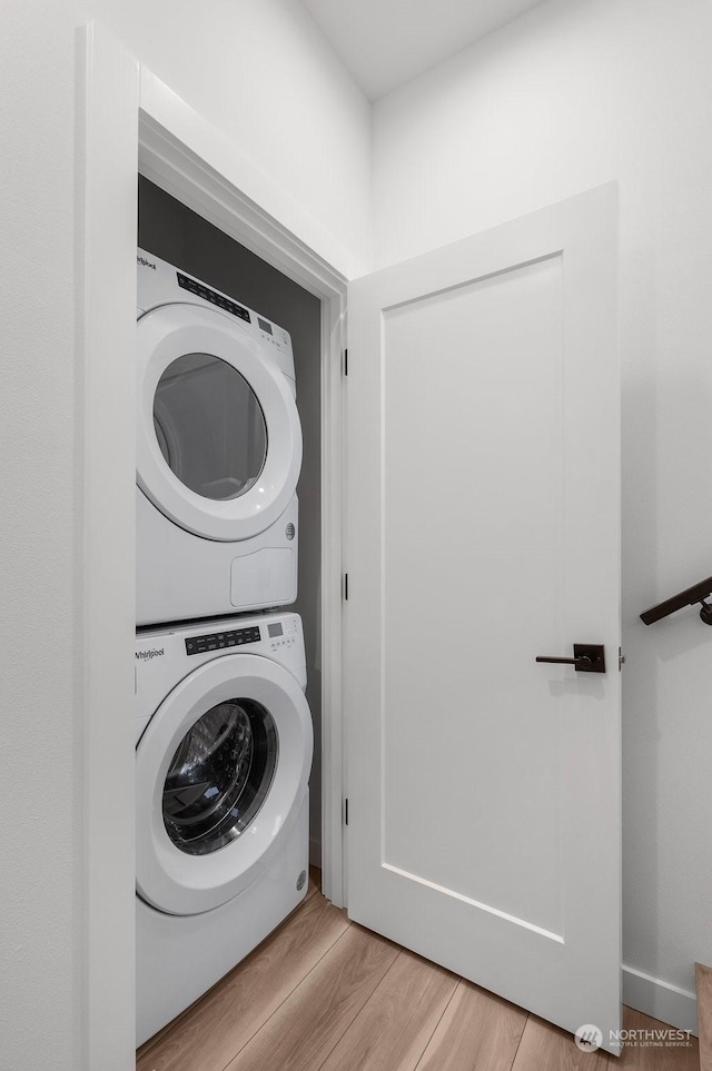 laundry area featuring stacked washer / dryer and light wood-type flooring