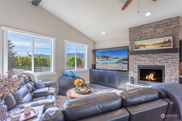 living room with a stone fireplace, lofted ceiling with beams, and ceiling fan