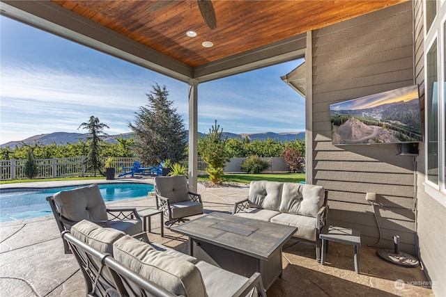 view of patio with a fenced in pool, an outdoor hangout area, a mountain view, and ceiling fan