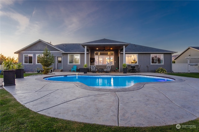 pool at dusk featuring a patio area and ceiling fan