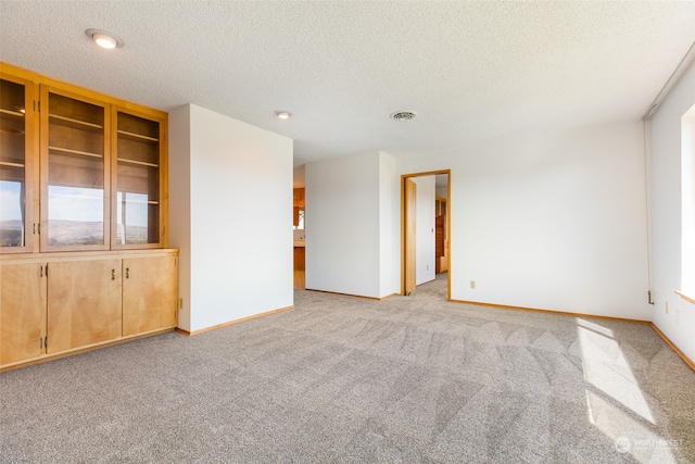 carpeted empty room featuring a textured ceiling