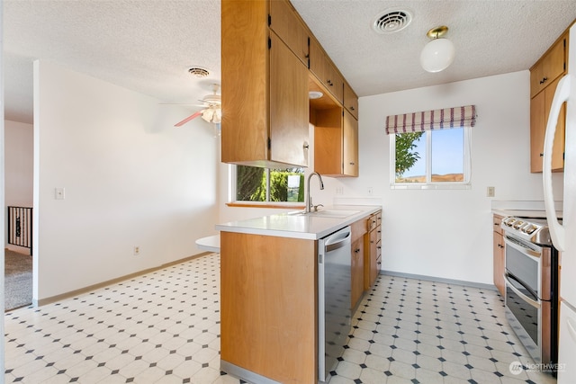 kitchen featuring ceiling fan, sink, kitchen peninsula, a textured ceiling, and appliances with stainless steel finishes