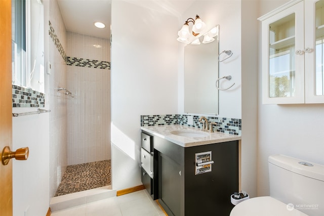 bathroom with vanity, tasteful backsplash, tiled shower, plenty of natural light, and toilet