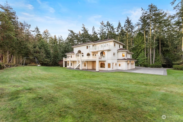 back of property with a yard, a patio area, and a balcony