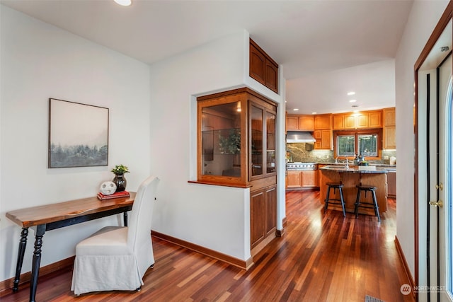 kitchen with a center island, dark wood-type flooring, a kitchen breakfast bar, backsplash, and appliances with stainless steel finishes