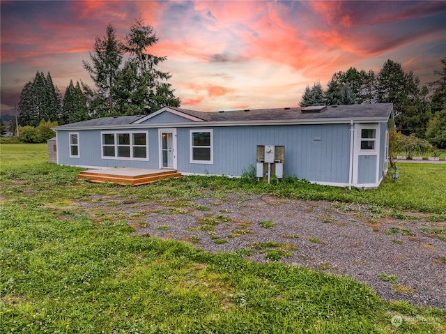 back house at dusk with a lawn and a deck