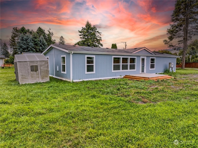 back house at dusk featuring a wooden deck, an outdoor structure, and a yard