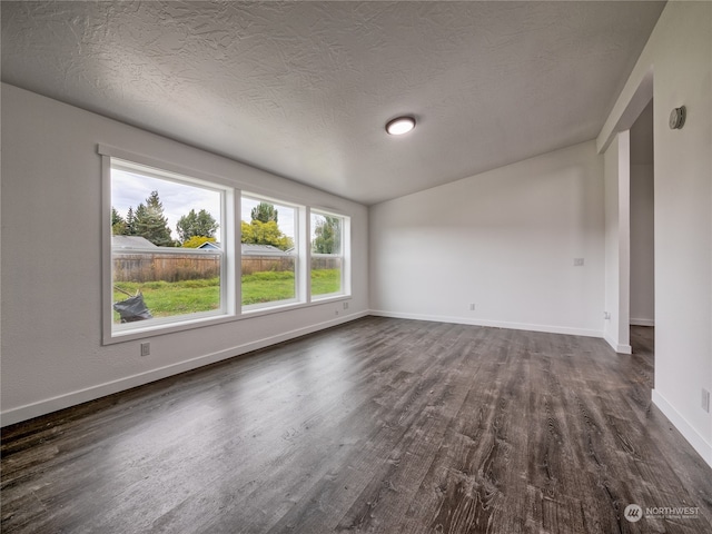 spare room featuring vaulted ceiling, a textured ceiling, and dark wood-type flooring