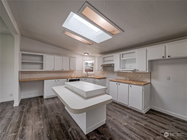 kitchen with white cabinetry, a center island, lofted ceiling with skylight, and dark hardwood / wood-style flooring