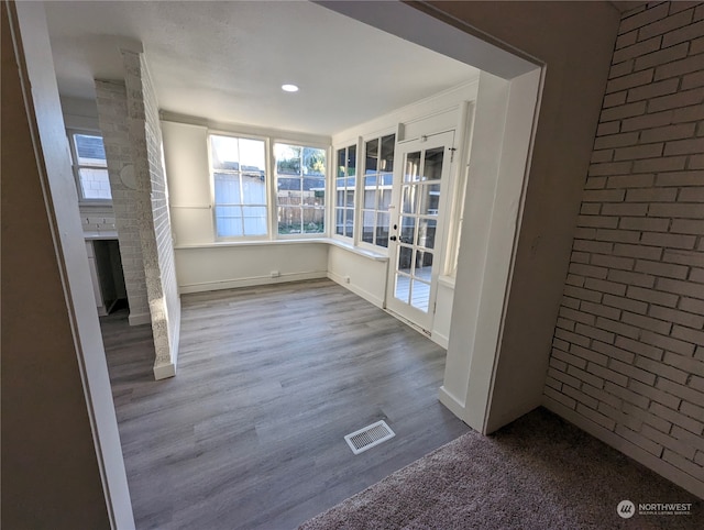 unfurnished living room with brick wall and hardwood / wood-style flooring