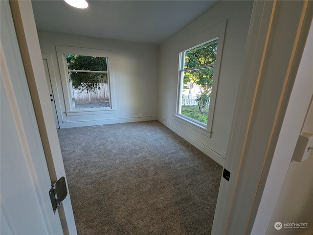 unfurnished room featuring dark colored carpet