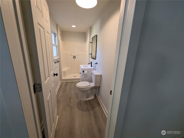 bathroom featuring a shower, hardwood / wood-style floors, and toilet