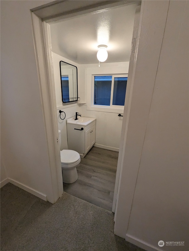 bathroom with hardwood / wood-style flooring, vanity, and toilet