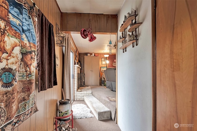 hallway featuring light colored carpet and wooden walls