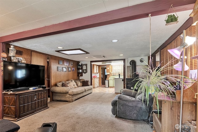 living room featuring a textured ceiling, wood walls, carpet flooring, and a wood stove