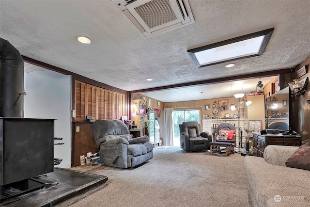 carpeted living room featuring wood walls, a textured ceiling, and a skylight