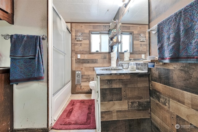 full bathroom with vanity, wooden walls, toilet, and combined bath / shower with glass door