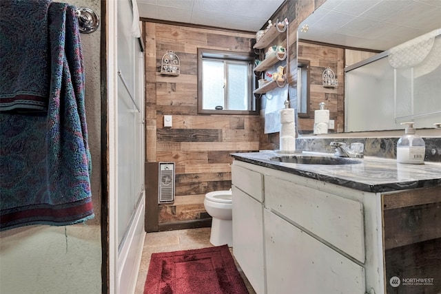 bathroom with vanity, wooden walls, a shower with shower door, and toilet