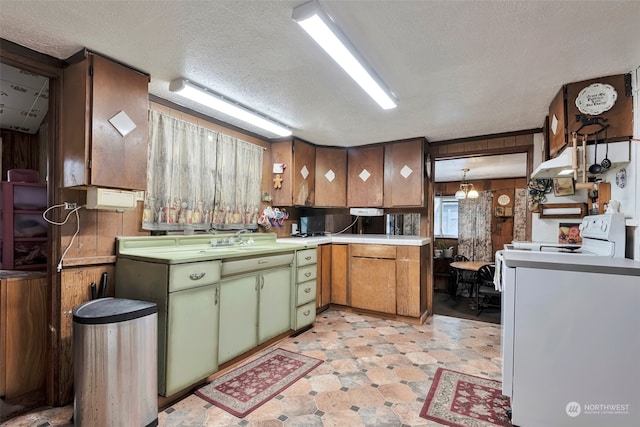 kitchen featuring a textured ceiling, wood walls, sink, and green cabinets