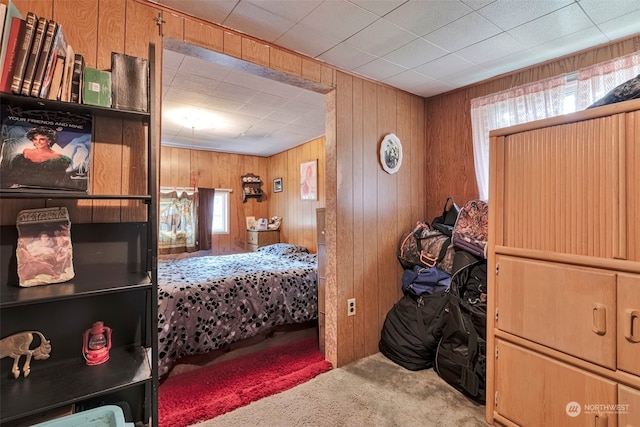 carpeted bedroom featuring wood walls