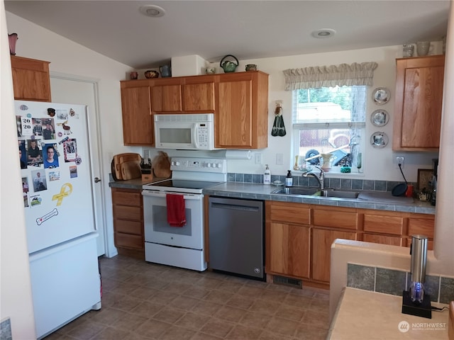 kitchen featuring lofted ceiling, sink, and white appliances