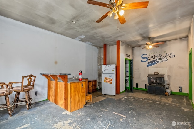 kitchen featuring ceiling fan, white refrigerator, kitchen peninsula, and a wood stove