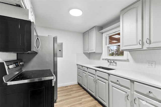 kitchen with sink, light hardwood / wood-style flooring, stainless steel appliances, and tasteful backsplash