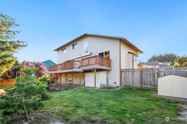 back of property with a yard, a wooden deck, and a shed