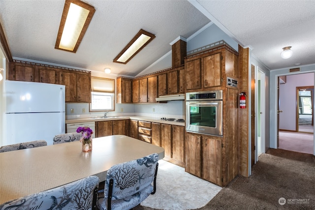 kitchen with vaulted ceiling, a textured ceiling, white appliances, and light colored carpet