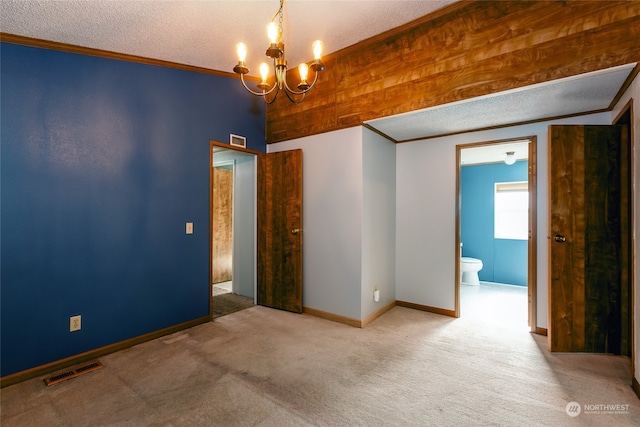 empty room with ornamental molding, carpet, a notable chandelier, and a textured ceiling