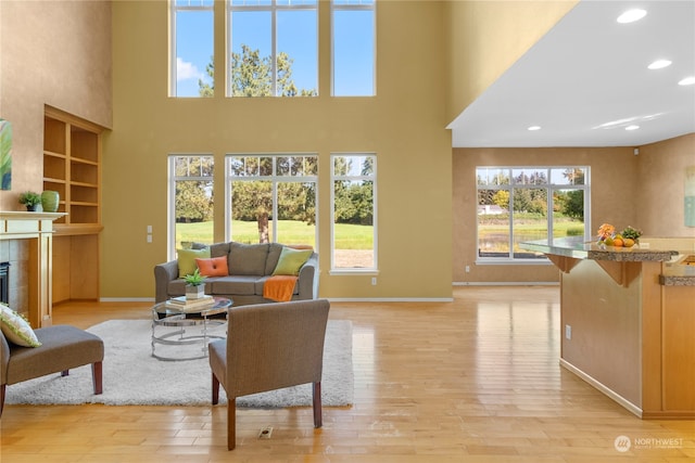 living room featuring a high ceiling, a tile fireplace, and light hardwood / wood-style flooring