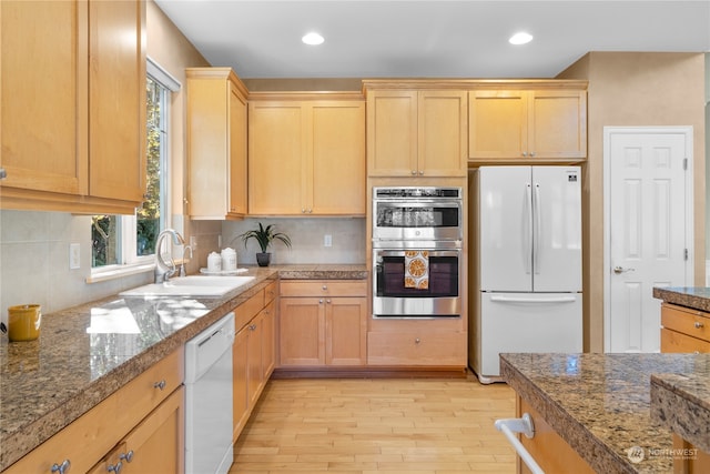 kitchen with white appliances, light hardwood / wood-style flooring, light brown cabinetry, decorative backsplash, and sink