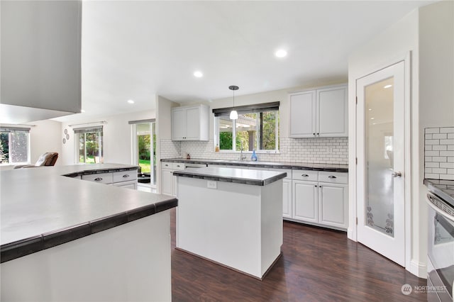 kitchen featuring backsplash, a kitchen island, dark hardwood / wood-style floors, white cabinetry, and hanging light fixtures