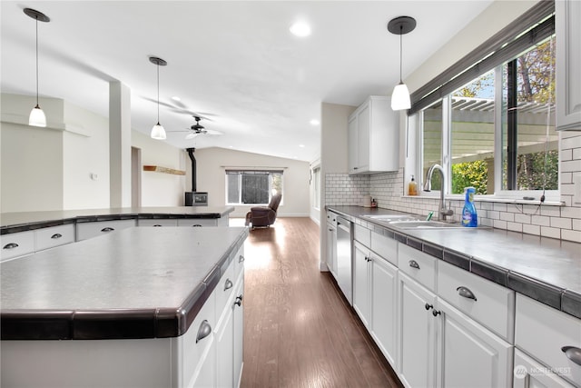 kitchen featuring stainless steel dishwasher, dark wood-type flooring, sink, white cabinets, and lofted ceiling