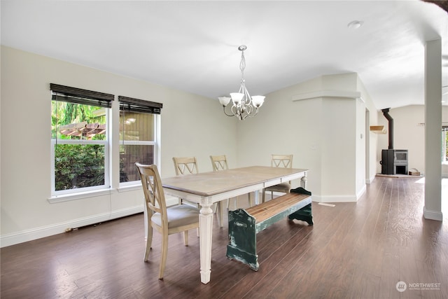 dining space featuring dark hardwood / wood-style flooring, an inviting chandelier, and a wood stove